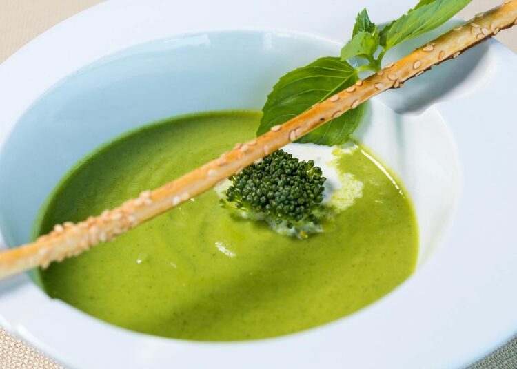 tazón de crema de guisantes verdes frescos con menta, fotografía cenital sobre fondo claro