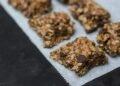 Granola casera dorada con avena, frutos secos y semillas, vista cenital en bol de madera