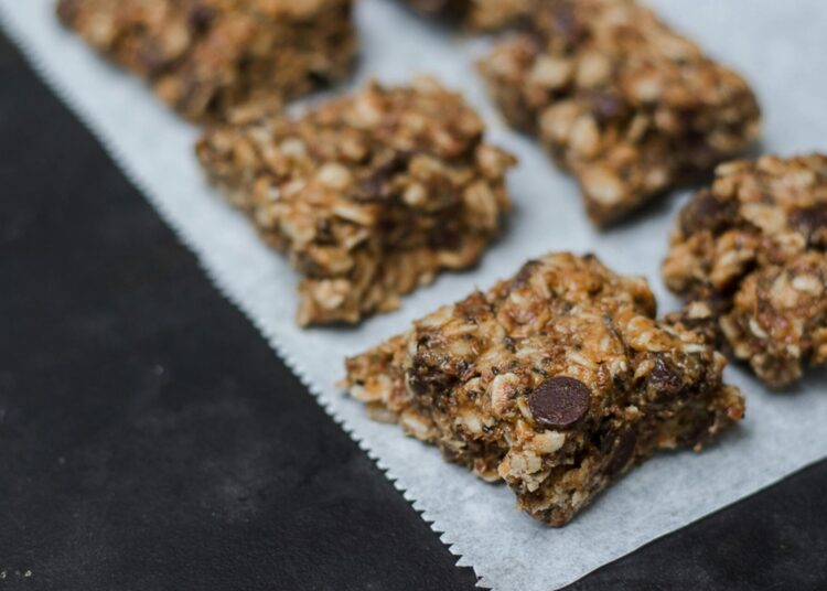 Granola casera dorada con avena, frutos secos y semillas, vista cenital en bol de madera