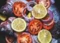 merluza al horno con tomates cherry y limón en una fuente, cena saludable mediterránea