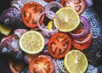 merluza al horno con tomates cherry y limón en una fuente, cena saludable mediterránea