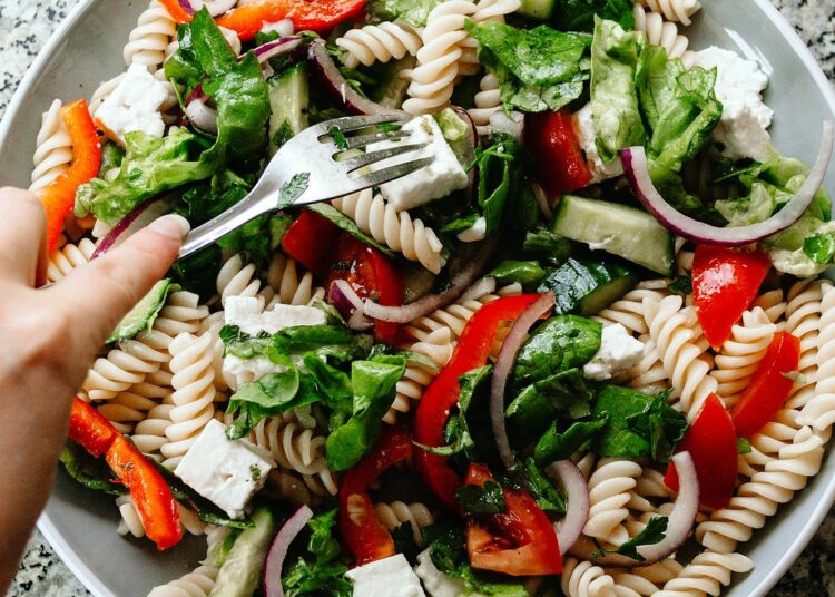 Ensalada de pasta saludable con verduras frescas, tomate y queso en un bol