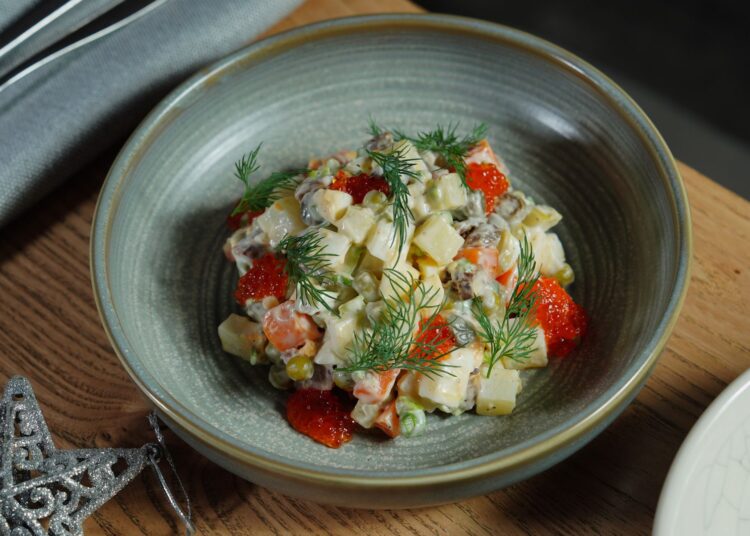 Ensaladilla rusa saludable cremosa servida en un bol con eneldo
