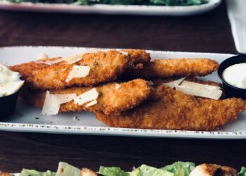 Varitas de merluza caseras al horno crujientes y empanadas servidas en un plato