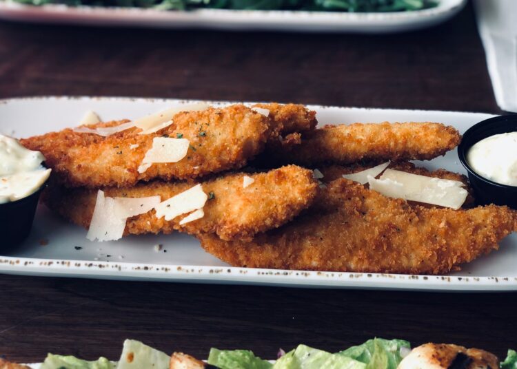 Varitas de merluza caseras al horno crujientes y empanadas servidas en un plato