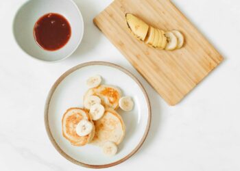 Tortitas de plátano y huevo caseras con rodajas de plátano fresco en un plato