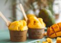 Helado de mango casero cremoso servido en copas con trozos de mango fresco