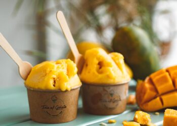 Helado de mango casero cremoso servido en copas con trozos de mango fresco