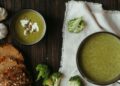 Bol blanco con crema fría de calabacín verde, decorada con un chorrito de aceite y hierbas frescas