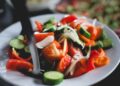 Pipirrana andaluza con tomate, pepino y pimiento verde en un bol, aliñada con aceite de oliva