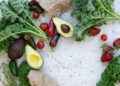 Alimentos ricos en potasio: aguacates, verduras de hoja verde, tomates y frutas frescas sobre mesa