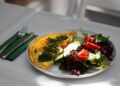 Tortilla de calabacín jugosa servida en plato con ensalada fresca de verduras