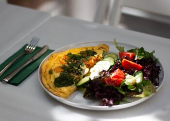 Tortilla de calabacín jugosa servida en plato con ensalada fresca de verduras