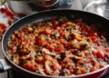 Pisto manchego cocinándose a fuego lento en una sartén con tomate, pimiento y calabacín