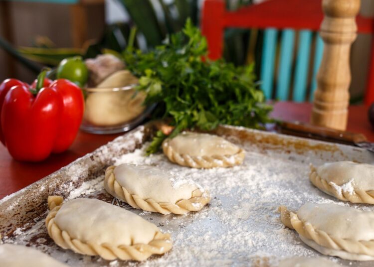 Empanadillas de atún al horno recién formadas sobre una bandeja lista para hornear