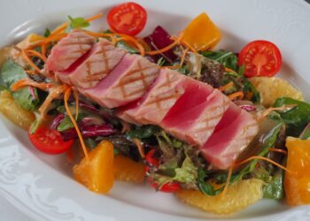 Tomates rellenos de atún servidos fríos con hierbas frescas sobre un plato