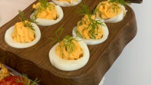 Bandeja con huevos rellenos de atún decorados con cebollino, listos para servir como aperitivo