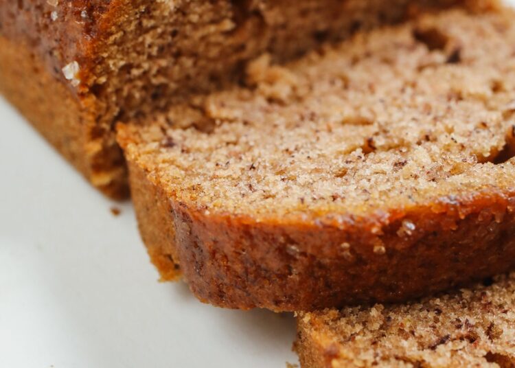 Pan de plátano saludable recién horneado y cortado en rebanadas sobre una tabla de madera