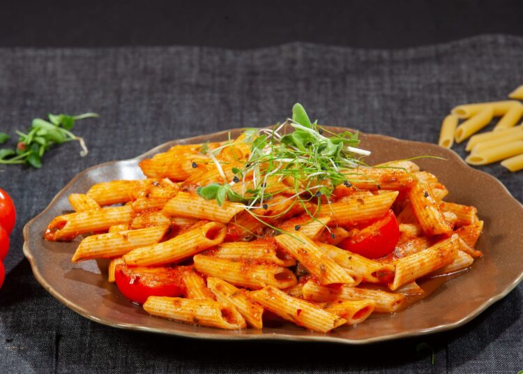 Plato de macarrones con tomate casero con albahaca fresca y queso rallado
