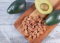 Almendras y aguacates sobre tabla de madera, alimentos ricos en vitamina E