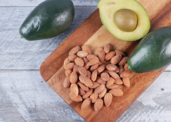 Almendras y aguacates sobre tabla de madera, alimentos ricos en vitamina E