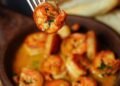 Gambas al ajillo recién hechas en sartén con ajo laminado y perejil