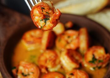Gambas al ajillo recién hechas en sartén con ajo laminado y perejil