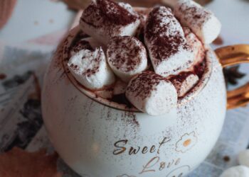 Taza de chocolate caliente casero cremoso sobre mesa de madera con hojas de otoño