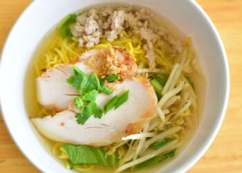 Plato de sopa de fideos casera con caldo de pollo dorado y fideos finos, lista para servir