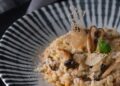 Risotto de setas cremoso servido en plato hondo con setas laminadas y queso rallado