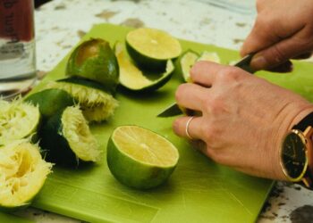 Manos cortando con un cuchillo de cocina sobre una tabla verde