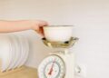 Persona pesando ingredientes en una báscula de cocina digital con un cuenco