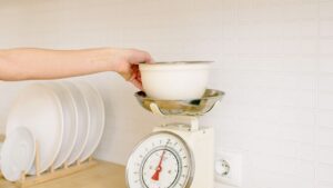 Persona pesando ingredientes en una báscula de cocina digital con un cuenco