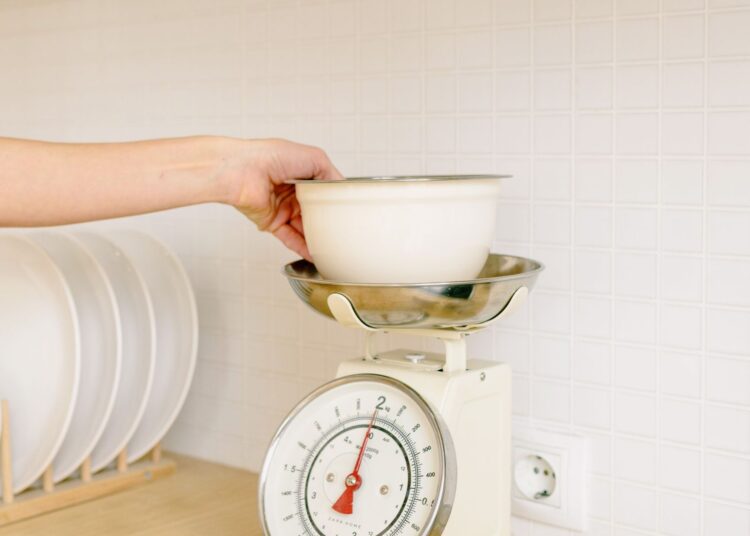 Persona pesando ingredientes en una báscula de cocina digital con un cuenco